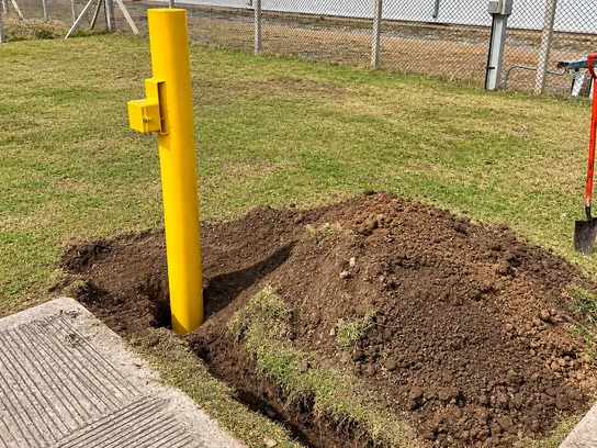 Caja de medición de potencial amarilla junto a la excavación para un ánodo, en una planta industrial.